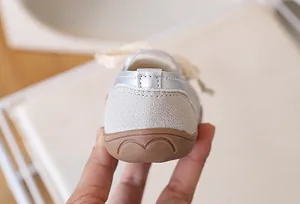 Dettaglio di sneakers argento per bambina con fiocco in pizzo e suola in gomma antiscivolo