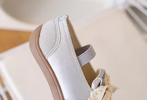 Dettaglio di scarpe Mary Jane argento da bambina con pizzo beige e cinturino elastico