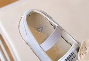 Dettaglio di sneaker argento da bambina con fiocchi di pizzo e solette con cuori