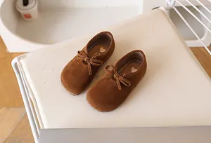 Détail de chaussures en daim marron pour filles avec nœud et cœur sur chaise blanche