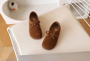 Détail de chaussures marron pour filles en suède avec nœud et semelle intérieure rétro