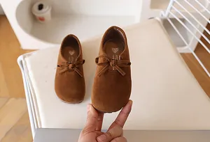 Gros plan de chaussures plates marron clair pour filles avec nœud et logo doré intérieur