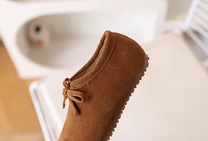 Détail de chaussures en daim marron pour enfants avec nœud et semelle en caoutchouc