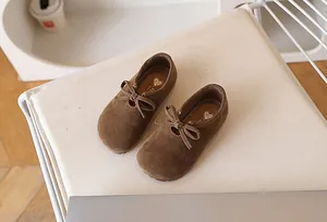 Détail de ballerines marron pour fille en daim avec nœud sur un siège moelleux
