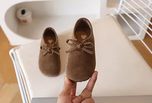 Détail de chaussures en daim marron pour filles avec un nœud et un design à bout rond