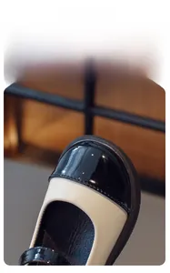 Close-up of contrast black patent leather toe and cream upper on girl's Mary Jane shoes