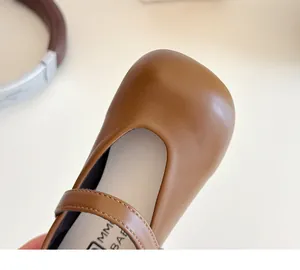 Close-up of brown Mary Jane leather shoes with Velcro strap and MM BABY brand detail