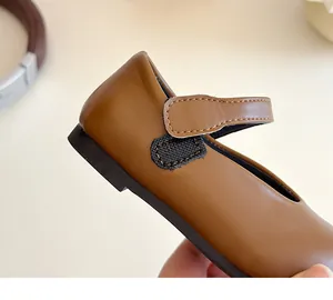 Close-up of hook and loop strap and stitching on brown Mary Jane shoes for girls