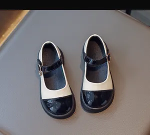 Close-up of Mary Jane girls shoes with black patent leather toe and heart charm detail