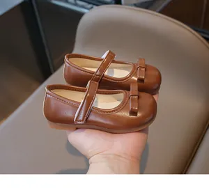 Close-up of brown girls' Mary Jane shoes with bow detail and velcro strap fastening