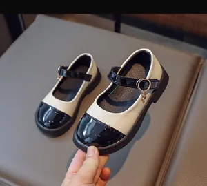 Detail of girls' Mary Jane shoes featuring black patent leather and beige matte contrast