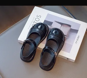 Close-up of black Mary Jane shoes for girls with patent leather toe and gold buckle