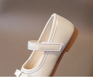 Close-up of cream Mary Jane shoes featuring bow detail and velcro strap for girls