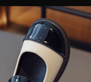 Close-up detail of the black patent leather toe and cream contrast on Mary Jane shoes