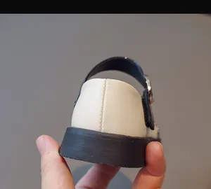 Detail view of stitched heel and thick rubber sole on girls' beige Mary Jane shoes