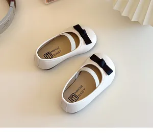 Draufsicht auf weiße Mary Jane Mädchenschuhe mit schwarzer Schleife und Gummiband
