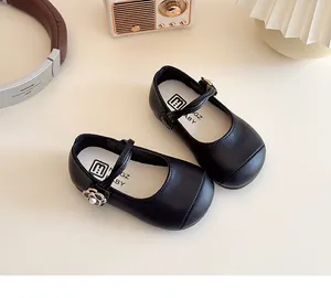Detail of girls' black Mary Jane shoes with pearl camellia flower on the strap