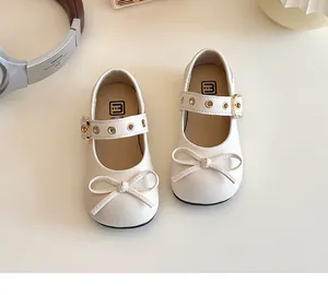 Draufsicht auf cremefarbene Mary Jane Mädchenschuhe mit dekorativen Schleifen und Schnallen