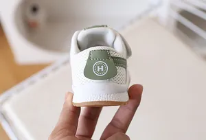 Close-up of baby sneaker heel with green leather patch and embossed H logo detail