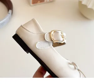 Details von cremefarbenen Mädchen Mary Janes mit goldener Schnalle und Klettverschluss