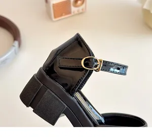 Detail von glänzend schwarzen Lackleder-Mary-Janes mit Blockabsatz und goldener Schnalle