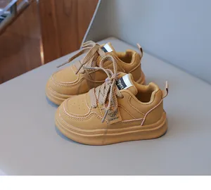 Close-up of yellow leather kids sneakers showing perforated toe box and flat woven laces