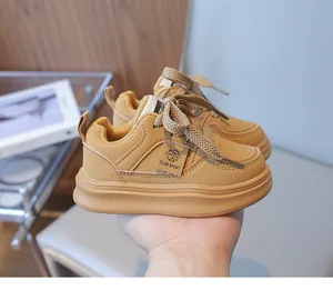 Detail of children's brown casual sneakers with thick soles and lace-up design in hand