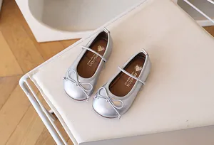 Detalle de zapatos Mary Jane plateados para niñas con lazo y correa elástica