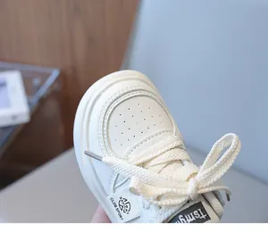 Close-up of children's white sneakers showing synthetic leather texture and stitching