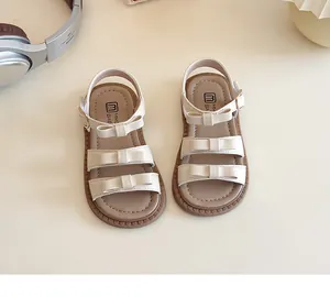Dettaglio di sandali beige per bambine con fiocchi decorativi e cinturini regolabili