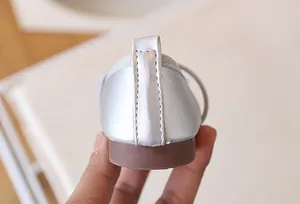 Detalle de zapatos plateados para niña con costuras precisas y suela de goma duradera