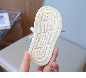 Detailed view of white children's sneaker rubber sole with anti-slip wave patterns