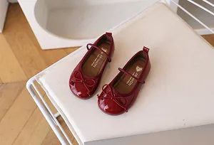 Vista superior de merceditas en charol rojo oscuro con detalle de lazo elegante