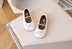 Detalle de zapatos Mary Jane blancos para niña con lazo y cuero sintético pulido
