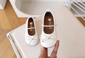 Detalle de zapatos Mary Jane de charol blanco con lazo y acabado brillante