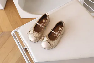 Vista superior de zapatos Mary Jane dorados para niñas con un lazo delicado y correa