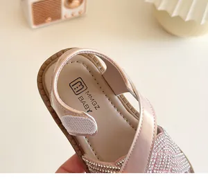 Detalle de sandalias para bebé rosa champán con pedrería brillante y cierre de velcro