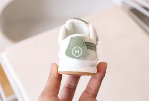Gros plan détaillé du talon en maille blanche avec logo en cuir vert sur chaussure bébé