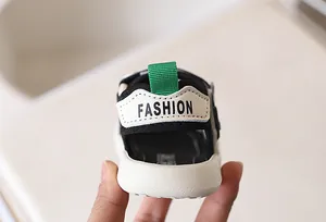 Detailopname van de hiel van de kindersandaal met groene treklip en Fashion-opdruk