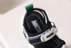 Detailopname van de hiel van de sandaal met groen treklipje en witte stiksels op de zool