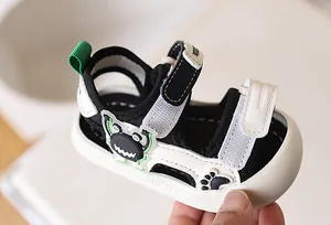 Detailopname van babysandalen met cartoon monster reliëf en klittenbandsluiting
