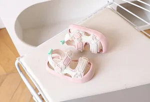 Detailopname van roze peutersandalen met klittenband en schattige cartoon kikker reliëf