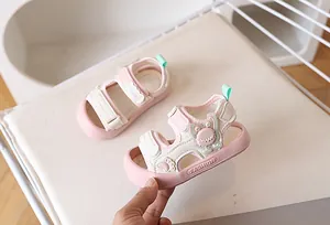 Detailopname van roze peutersandaal met cartoonmonster-ontwerp en klittenbandsluiting