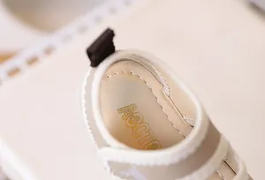 Detailed close-up of soft baby sandals with premium stitching and beige faux leather finish
