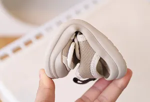 Close-up of flexible soft beige toddler sandal sole being bent to show flexibility