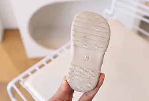 Close-up of flexible beige baby sandal sole with anti-slip grooves and size 18 marking