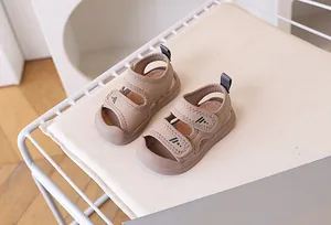 Macro detail of toddler closed-toe sandals with dual hook-and-loop straps in beige