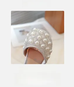 Dettaglio di sandali argentati da bambina con perle a cuore e strass luminosi e scintillanti
