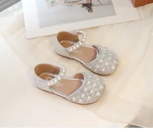 Dettaglio di sandali argentati da bambina con perle e strass luccicanti