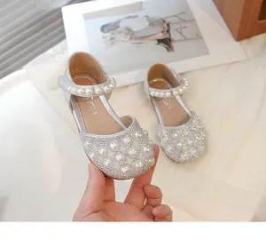 Dettaglio dei sandali argentati da bambina con strass luccicanti e cuore di perle
